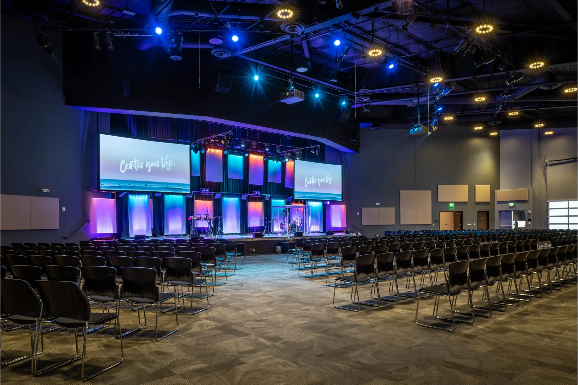 Visionary construction at Centerpoint church designed by Visioneering Studios. Space pictures the a stage and seating for guest to gathering to worship and hear a message