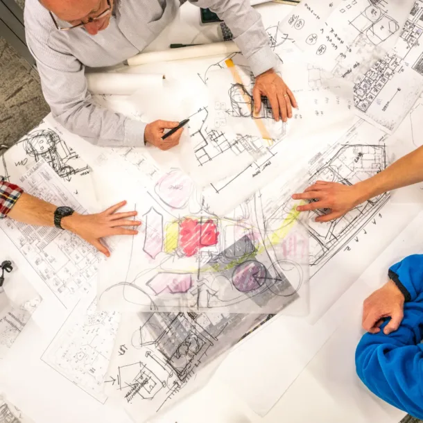 op-down view blueprints different hands pointing in different directions—symbolizing misalignment and premature decision-making. church building design mistakes 2 - 4 Team Hazards That Can Derail Your Project Before It Begins