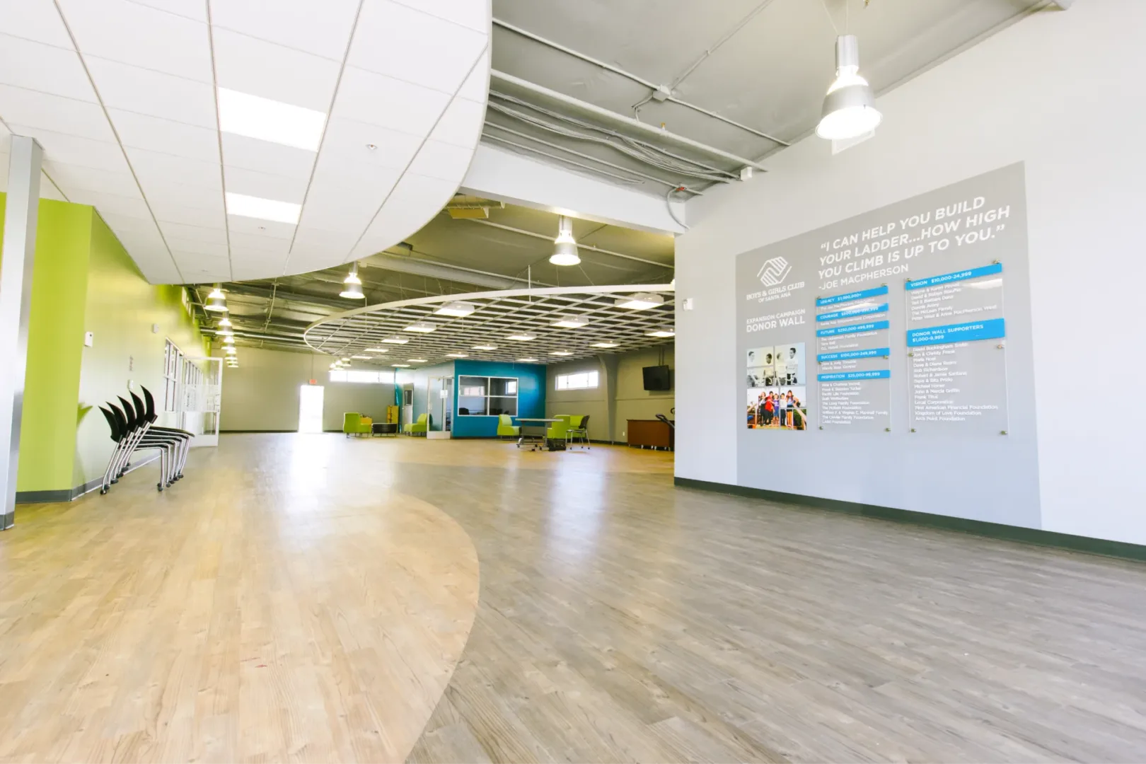 Lobby interior of Boys & Girls Club teen center designed by Visioneering Studios, featuring donor wall with acrylic signage, mission graphics, and Joe MacPherson quote.