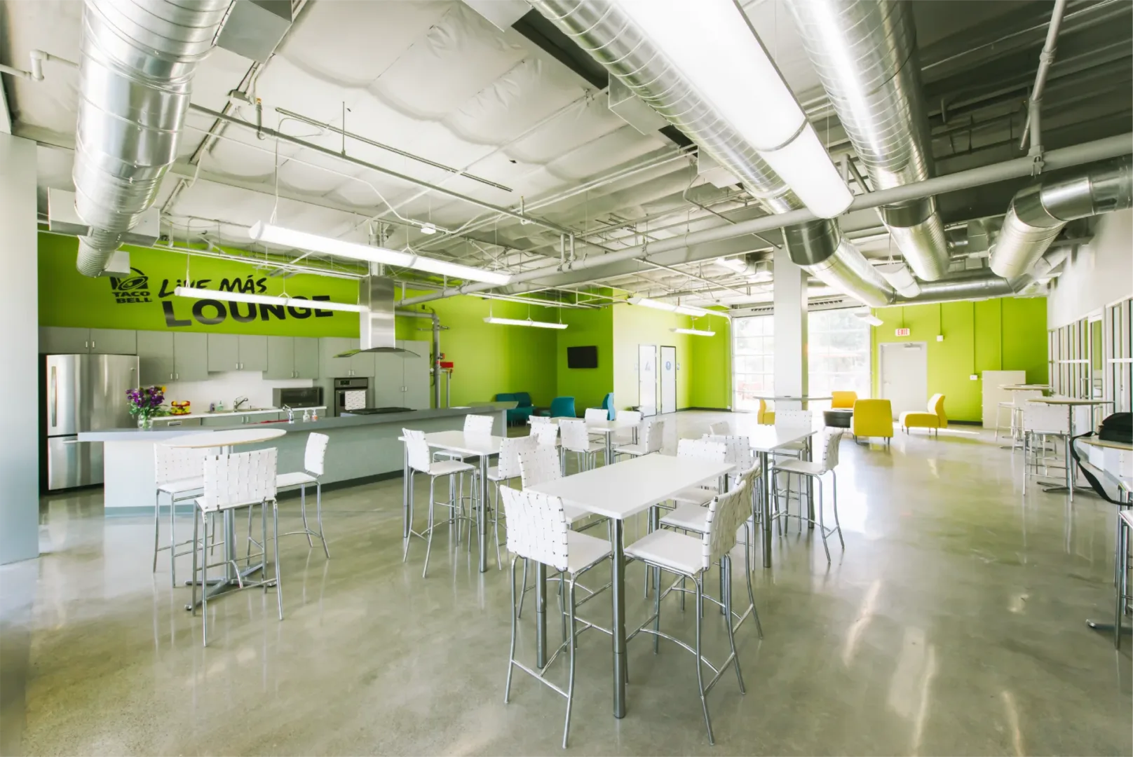 Interior of Boys & Girls Club kitchen with bright lime green walls, white tables and chairs, and modern finishes by visioneering studios - interior design studio