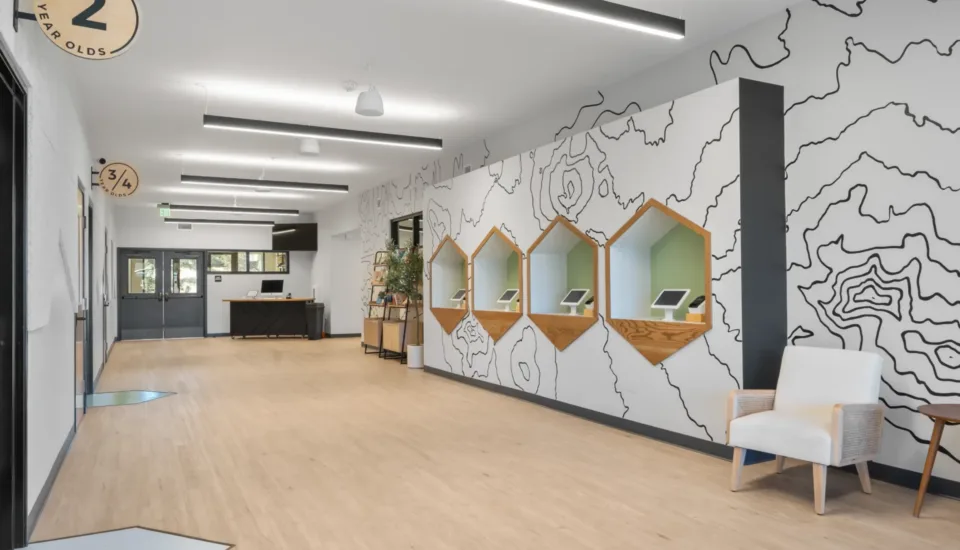 Kids check-in area at Grace Bible Church featuring natural design elements, topographic line graphics, and room ID signage by Visioneering Studios