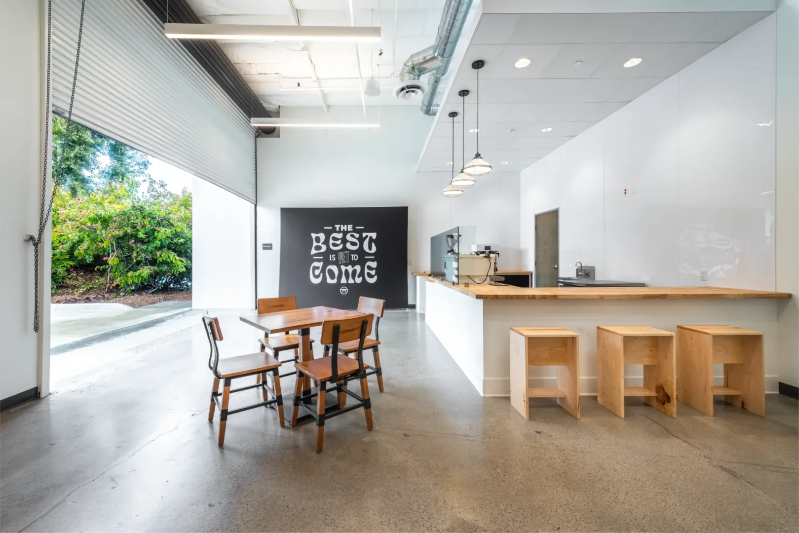 build design of mesa church new warehouse space which includes a new cafe. in the photos it is highlighting the garage style door rolled up that leads people right to the cafe
