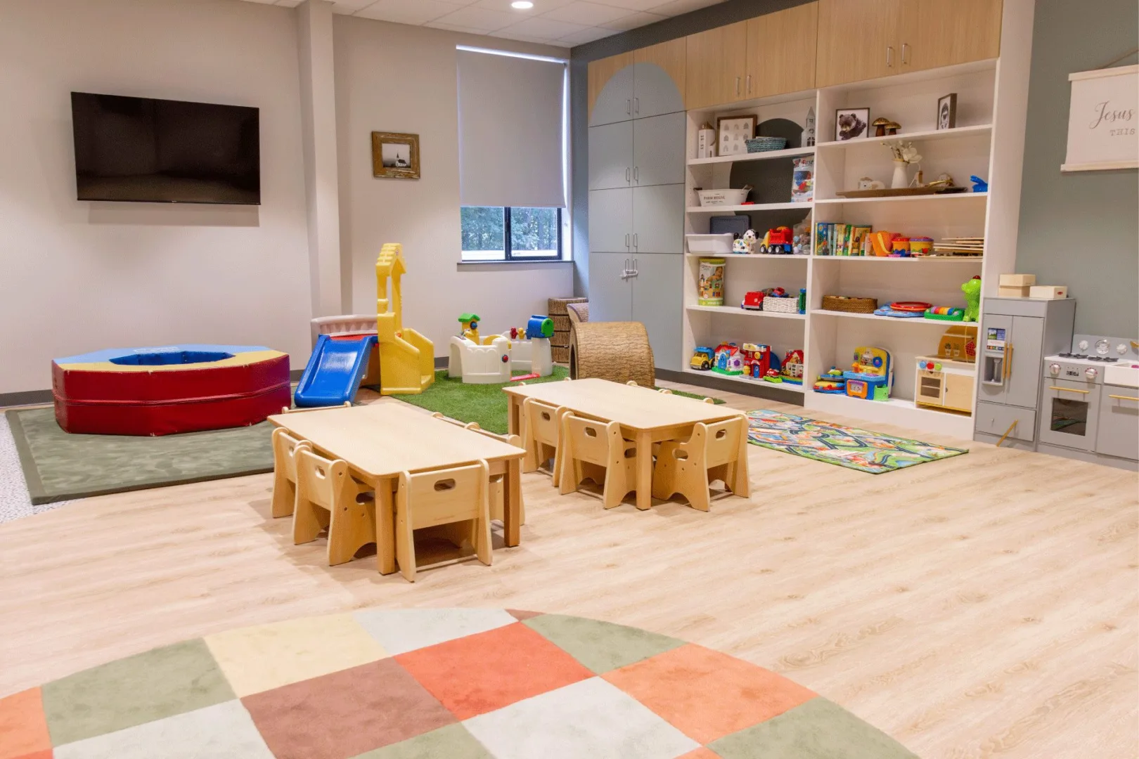 A preschool classroom designed for Gracepoint Kids with child-sized furniture, organized toy storage, play equipment, and a calming, modern interior created by Visioneering Studios.