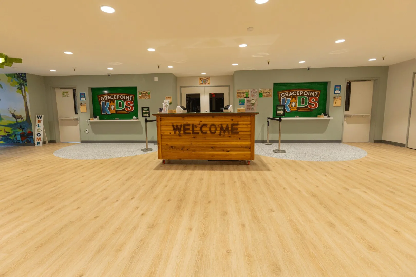 A central welcome desk inside the Gracepoint Kids check-in area, surrounded by branded signage and clean, modern finishes designed by Visioneering Studios.