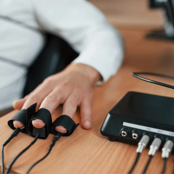 Close-up of a hand connected to a polygraph lie detector test, representing the importance of asking the right questions when choosing a church architect